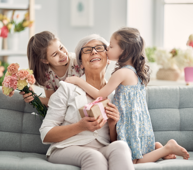 Dos niñas abrazan y dan regalos a su abuela