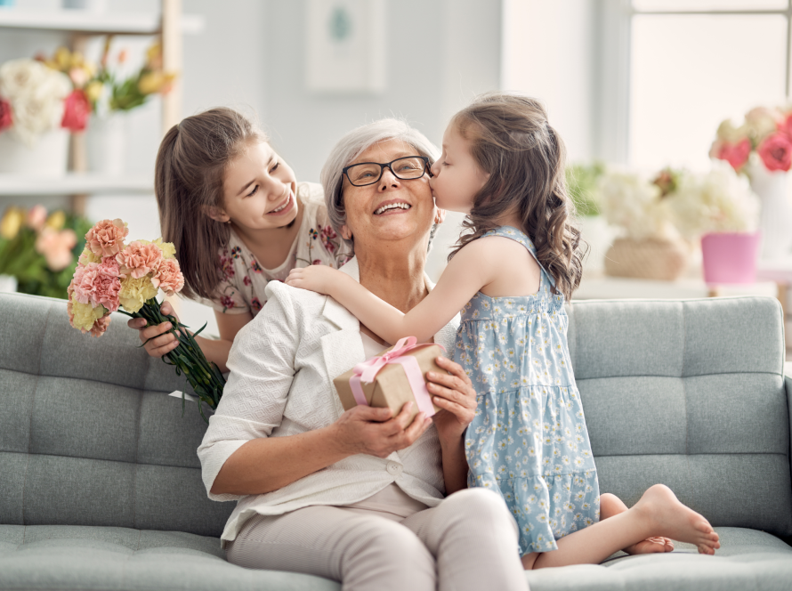 Dos niñas abrazan y dan regalos a su abuela