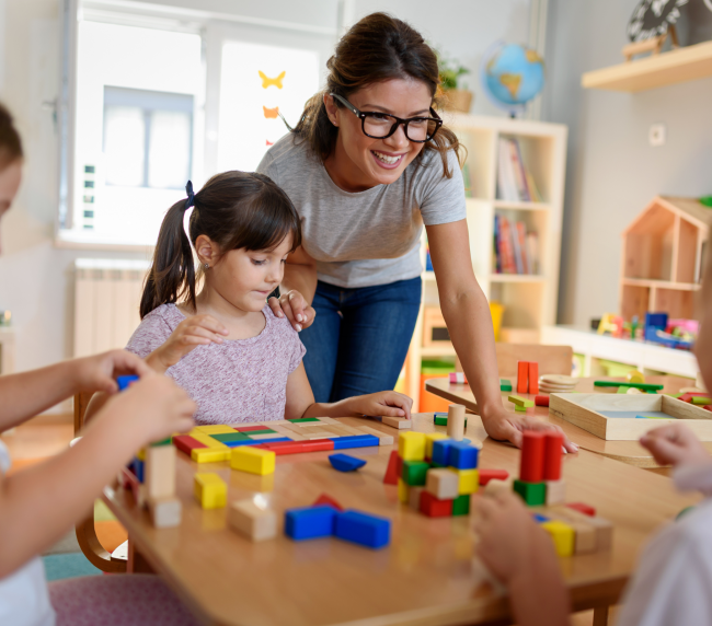 Niños jugando con bloques en una sala de Centro Timón, acompañados por una profesional.