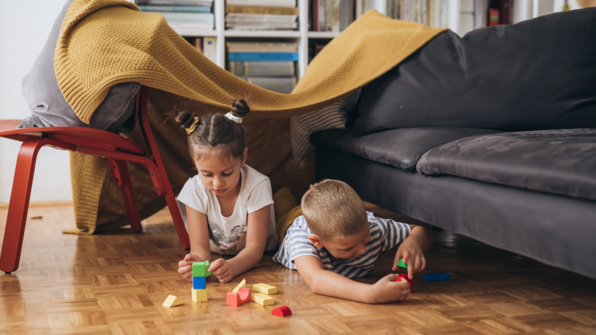 Dos niños pequeños juegan en el living de su casa